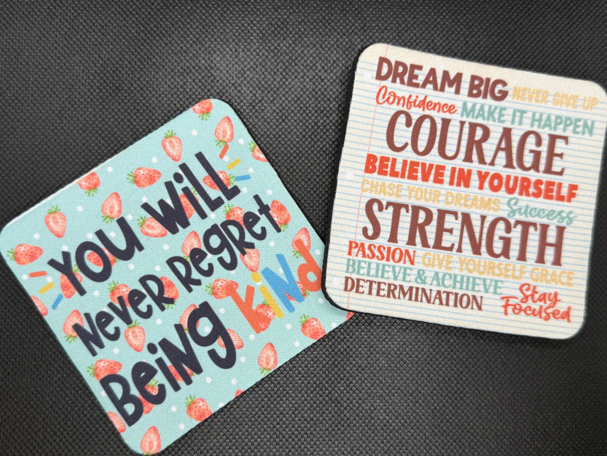 Two motivational coasters on a dark surface