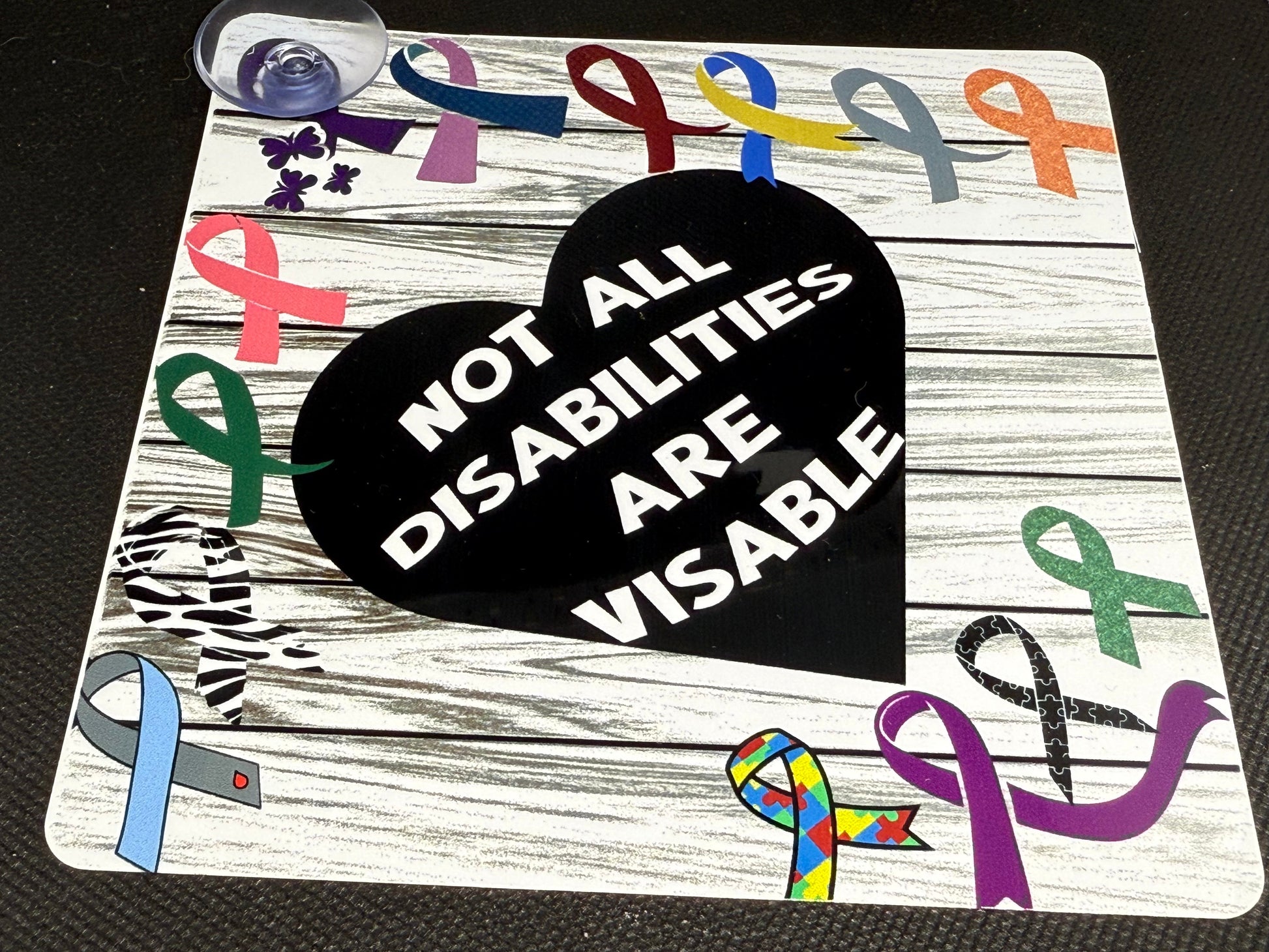 Decorative sign with colorful ribbons and a black heart with text on a wooden background